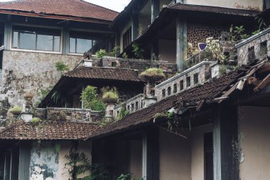 Kirli duvarları ve kırık çatısı olan terk edilmiş bir binanın karanlık fotoğrafı.