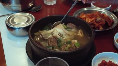 Mantarlı kaşık Kore çorbası ve masada duran et.