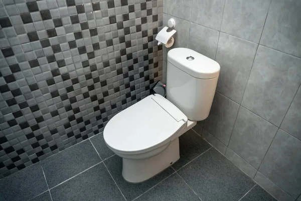 Seramik duvarlı, tuvalette kapalı beyaz bir tuvaletin fotoğrafı.