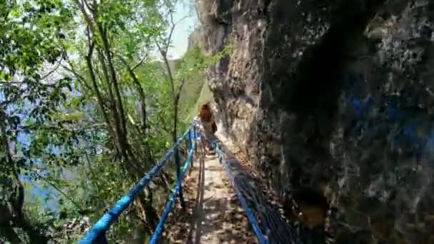 海と岩の見える高い山の崖への古い岩の階段上の適切な人の一人のビデオ — ストック動画