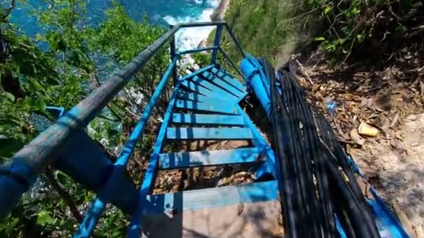 海と岩の見える高い山の崖に古い金属の階段上の適切な人の一人のビデオ — ストック動画