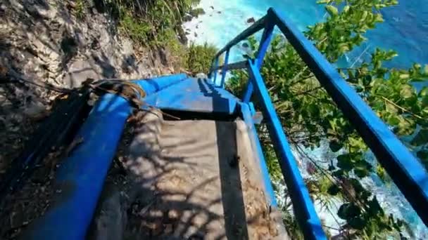 Vidéo à la première personne d'une personne convenable sur un vieil escalier en bois menant à une falaise sur une haute montagne avec vue sur la mer et les rochers 
