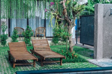 Yeşil bahçede güneşli yataklı ve güneşli havzalı bir fotoğraf. 