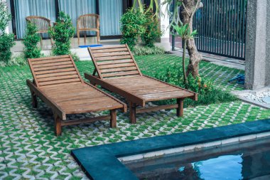 Yeşil bahçede güneşli yataklı ve güneşli havzalı bir fotoğraf. 