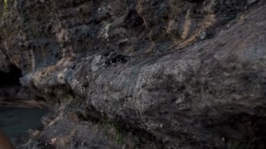 Genç, yakışıklı ve cesur Avrupalı bir adam kayaların arasında yürüyor ve onlara elleriyle dokunuyor.