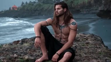 Yüzünde çizimler olan genç, yakışıklı ve cesur bir Avrupalı sahildeki mesafeye bakıyor.