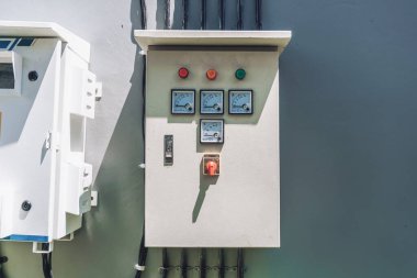 Sokakta duvara asılı beyaz renk ve voltaj göstergeleri olan büyük beyaz bir elektrik panelinin fotoğrafı.