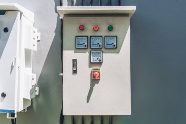 Sokakta duvara asılı beyaz renk ve voltaj göstergeleri olan büyük beyaz bir elektrik panelinin fotoğrafı.