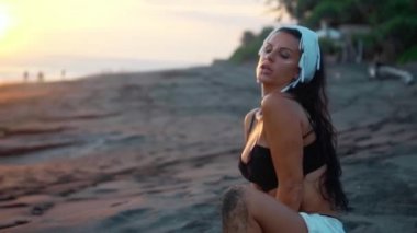 Kumun üzerinde oturan vücudu makyajlı, esmer, güzel bir Avrupalı kızın videosu.