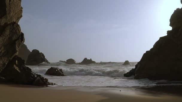 Surf en una playa de arena entre las rocas. Moción lenta — Vídeos de Stock