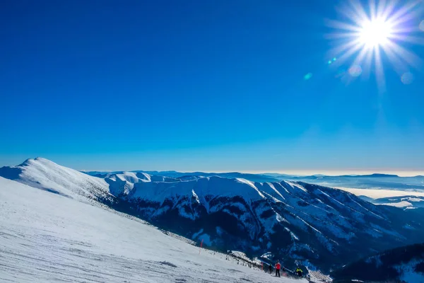 Зимнее солнце над горными вершинами и лыжным склоном — стоковое фото