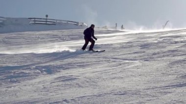 Güneşli kar kaplı kayak yamacı. Tanınmayan kayakçı bir dönüş yapıyor. Yavaş çekim