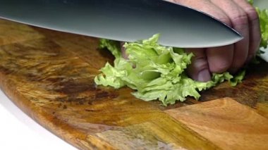 Tahta kesme tahtası. Erkeklerin elindeki bıçak bir sürü salata keser. Kapatın. Yavaş çekim