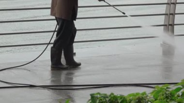 Singapore. Quay Marina Bay. Overcast weather. Worker washes the Embankment. Feet in rubber boots close-up. Slow motion
