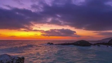 Kaya sahili. Gökyüzündeki birçok bulut şafağı inanılmaz renklerle renklendiriyor. Zaman aşımı