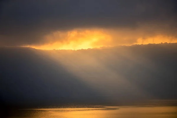 Hintergrund mit Sonnenstrahlen durch schwere Wolken — Stockfoto