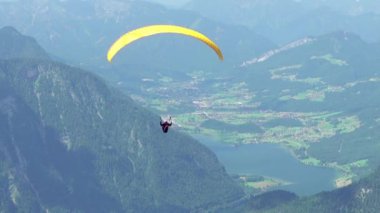 Avusturya, Obertraun. Sarı paraglider dağların ve vadilerin üzerinde uçuyor