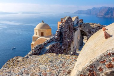 Yunanistan. Güneşli havada Santorini (Thira) adası. Oia 'daki kalderanın üzerindeki kilise ve eski kalıntılar. Deniz panoramik görünümü