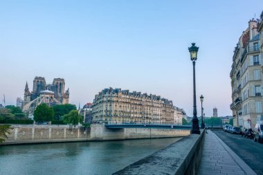Fransa. Yaz sabahının erken saatlerinde Seine Nehri 'nin setinde ve 2019 yangınından sonra Notre Dame' ın restorasyonunda. Park etmiş arabalar ve motosikletler.