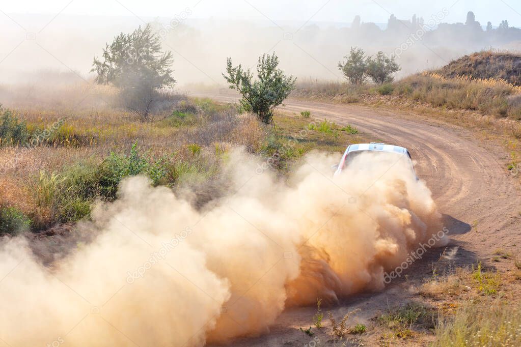 Summer dry dirt road. Sunny day. A car picks up a lot of dust at high speed