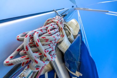  Mavi gökyüzü. Yelkenli bir yatın direğinin en alt görüntüsü. Bir halat ve diğer ipler.