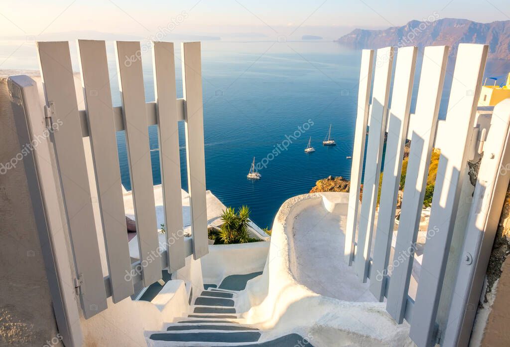 Greece. Santorini. Thira island. White gate and steps down. Seascape and yachts from the height of the caldera