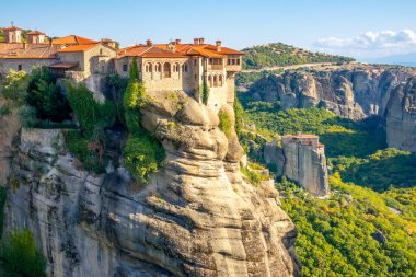 Yunanistan. Meteora 'da yaz güneşli bir gün. Kayalıklarda kırmızı çatıları olan manastır.