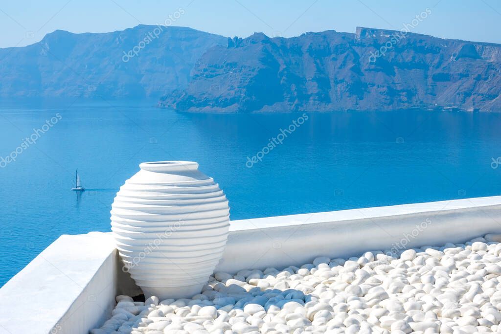 Greece. Sunny day on Santorini. White pebbles and a stone vase. Seascape with rocky islands