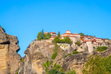 Yunanistan. Meteora 'da açık bir yaz günü. Bulutsuz mavi gökyüzüne karşı kırmızı çatıları olan birkaç kaya manastırı.