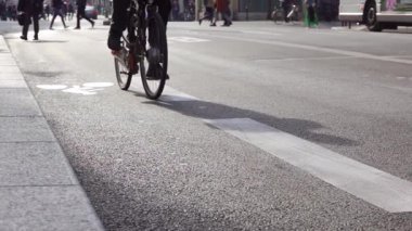 Şehir caddesi güneşli havada. Bisikletçi bisiklet yolu boyunca tanınmaz halde. Yavaş çekim