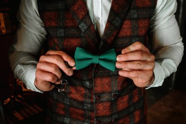 Yakışıklı damat yeşil bir papyon tutuyor..