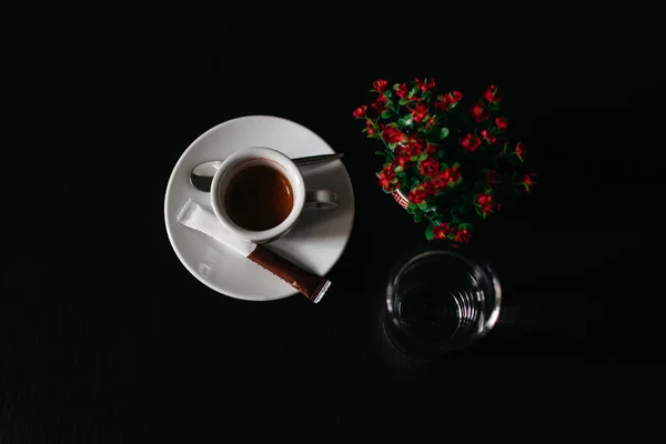 cup with coffee and flowers on black background