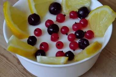 Siyah ve kırmızı üzümlü süt kreması ve beyaz kasede limon.