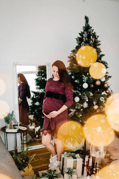 Noel Ağacının Yanında Duran Kırmızı Elbiseli Güzel Hamile Kadın — Stok fotoğraf