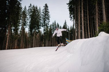 Karpatya dağlarında kar üzerinde sıçrama tahtasından kayak yapan bir adam.
