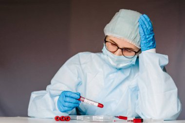 Corona virüsü. Solunum maskeli hemşire kan testi yapıyor. Sonuç pozitif. Hızlı bir şekilde Coronavirus, Çin 'e yayılıyor. 2019 nCoV için kan örneği içeren tüp. Salgın.