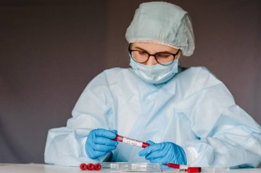 Solunum maskeli hemşire kan testi yapıyor. Sonuç pozitif, hızla Coronavirus yayılıyor. 2019 nCoV için kan örneği içeren tüp. Salgın Corona virüsü salgını.