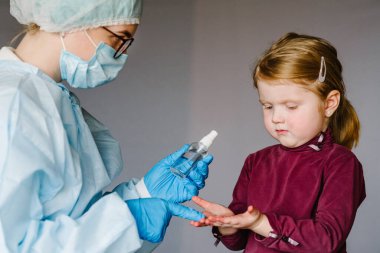 Hemşire ya da doktor el dezenfektanı jeli kullanır. Ellerini ovuşturur, çocuk ellerini ovuşturur, koronavirüs salgınını önler. Çocuk antibakteriyel sabun kullanıyor..