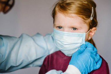 Coronavirus. Hemşire, koruyucu giysili doktor, çocuk için yüzünde tıbbi maske var. Covid-19 enfeksiyonuna karşı önleyici önlemler. Gribe karşı korunma kavramı, korona virüsü salgını.