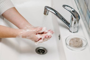 Coronavirus önleme. Ellerini antibakteriyel sabunla yıka ve sıcak akan suyla tırnaklarını ve parmaklarını lavaboda ovala. El yıkama. Salgın Covid-19. Grip hastalığının önlenmesi.