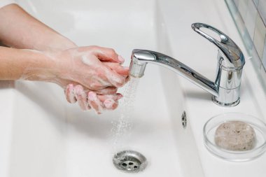 El yıkama. Coronavirus önleme. Ellerini antibakteriyel sabunla yıka ve sıcak akan suyla tırnaklarını ve parmaklarını lavaboda ovala. Salgın Covid-19. Grip hastalığının önlenmesi.