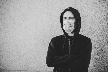 Coronavirus. Covid-19 hastalığının yayılması için maske takan genç bir adam. SARS-CoV-2 'ye karşı. Salgın. Salgın hastalık. Sağlığınızı koruyun. Karantina kavramı. Siyah beyaz fotoğraf.