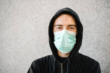 Coronavirus. Gri duvar arka planında tıbbi koruyucu maske takan bir adam. Covid-19 'u, gribi önle. Şehirde kötü hissediyorum. Birinin yardıma ihtiyacı var. Virüs, salgın hastalık, panik konsepti.