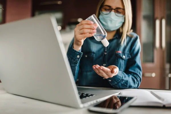 Coronavirus. Dezenfekte jeli. İş kadını karantinada koruyucu maske takıyor. Mikropları yok etmek için bakteriyel jel temizliyorum. Evde kal. Kız öğreniyor, dizüstü bilgisayar kullanarak. Bağımsız.