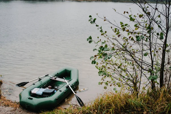 釣りのタックルを持つ箱とインフレータブルボートは 自然を背景に海岸近くの水 湖に立っています 釣りの背景 — ストック写真