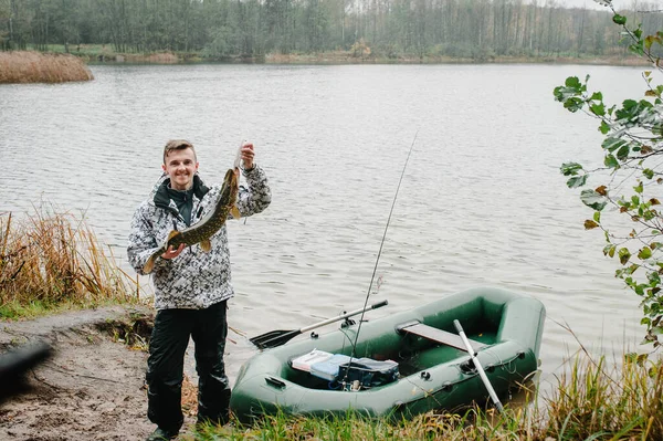 快乐快乐的年轻渔夫在湖水和大自然的背景下 在船边抓着一条大鱼 渔业背景 接得好小鱼 安格勒 关门了 — 图库照片