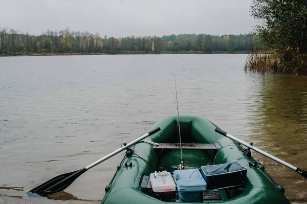 An inflatable boat, with boxes with fishing tackles, is standing on the water, pond, lake, near the shore on the background of tree, nature. Fishing background. boat with oars.