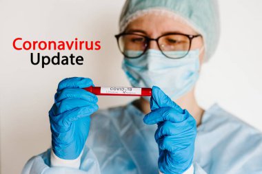 Coronavirus güncelleme metni. Doktor, hemşire, koruyucu kıyafetli bilim adamı biyolojik numuneli bir test tüpü tutuyor. Covid-19. Laboratuvar testi - negatif sonuç.
