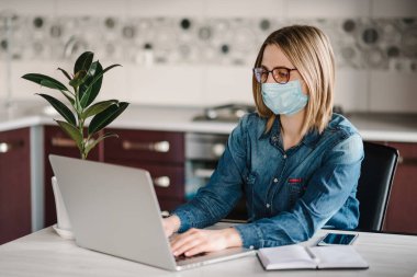 Coronavirus. Karantinada koruyucu maske takan bir iş kadını. Evde kal. Kız ev bilgisayarını kullanarak öğreniyor. Serbest çalışıyorum. İletişim ve teknoloji kavramı.