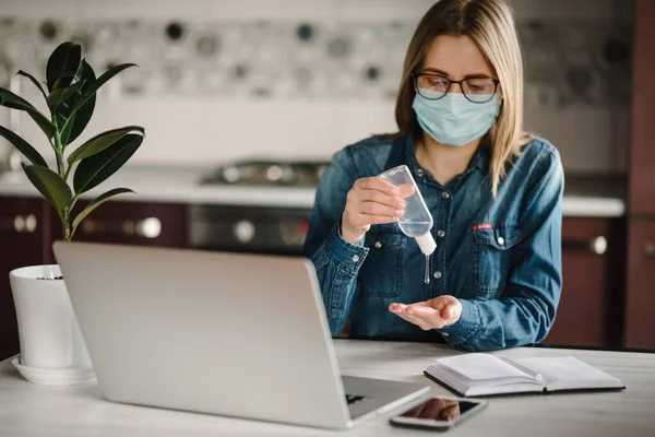 Coronavirus. Dezenfekte jeli. İş kadını karantinada koruyucu maske takıyor. Mikropları yok etmek için bakteriyel jel temizliyorum. Evde kal. Kız öğreniyor, dizüstü bilgisayar kullanarak. Bağımsız.